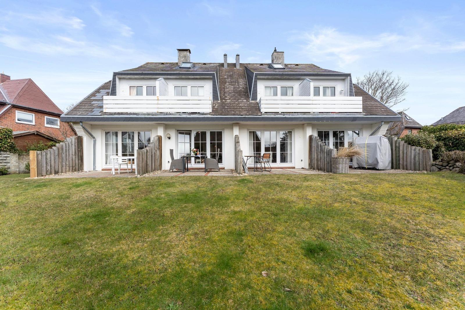 House with large garden and terrace with seating areas.