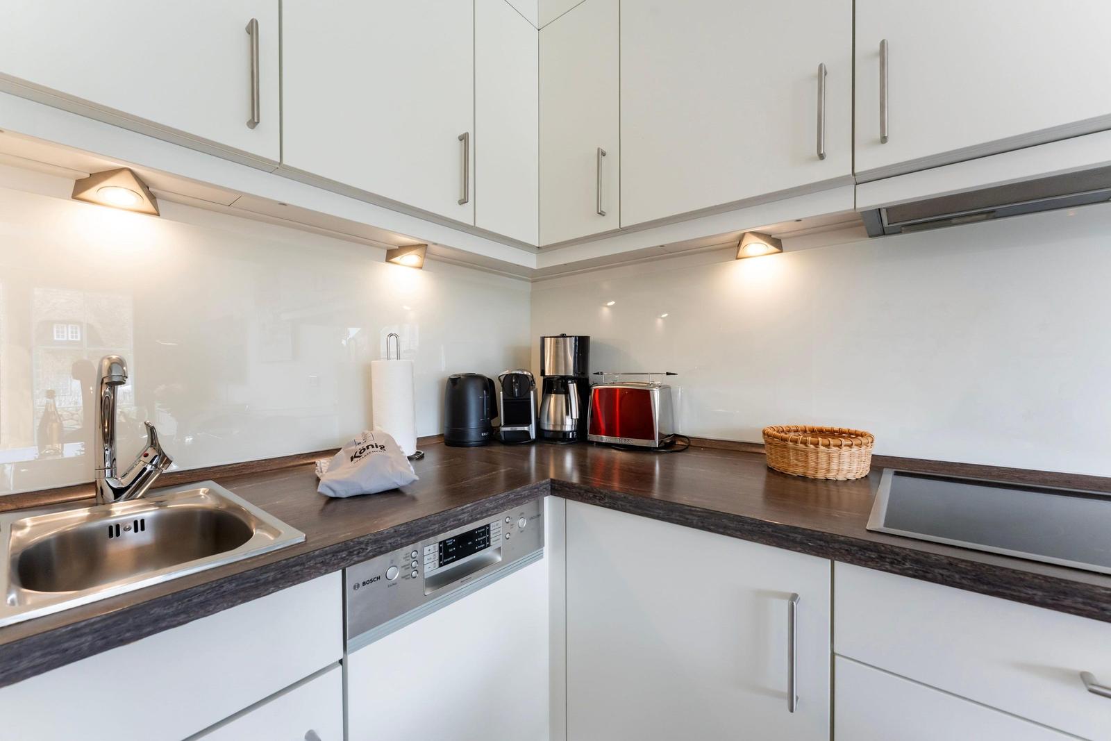 Kitchen with white cabinets, dark countertop, and stainless steel sink.