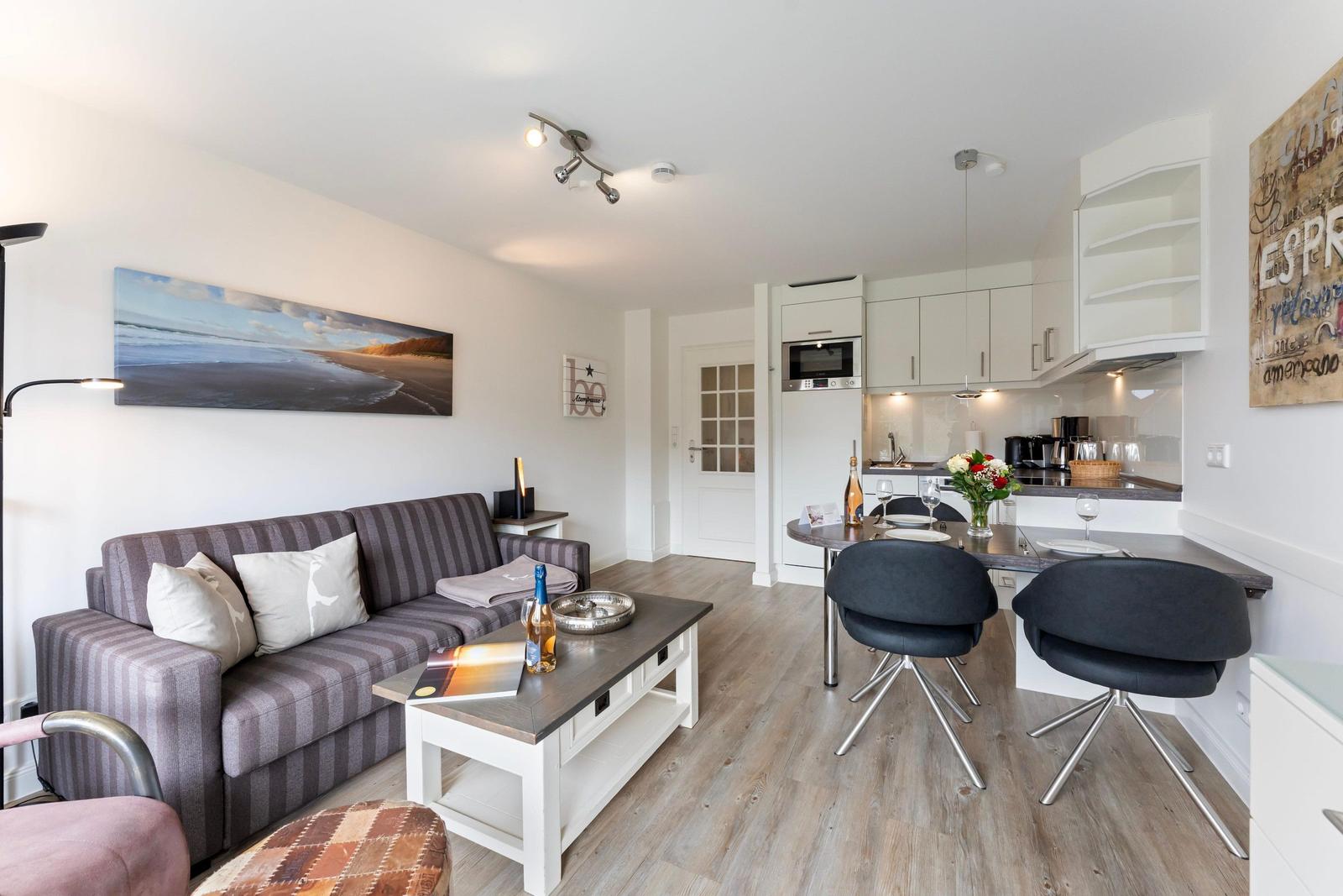 Living and kitchen area with sofa, dining table, and kitchen cabinets.