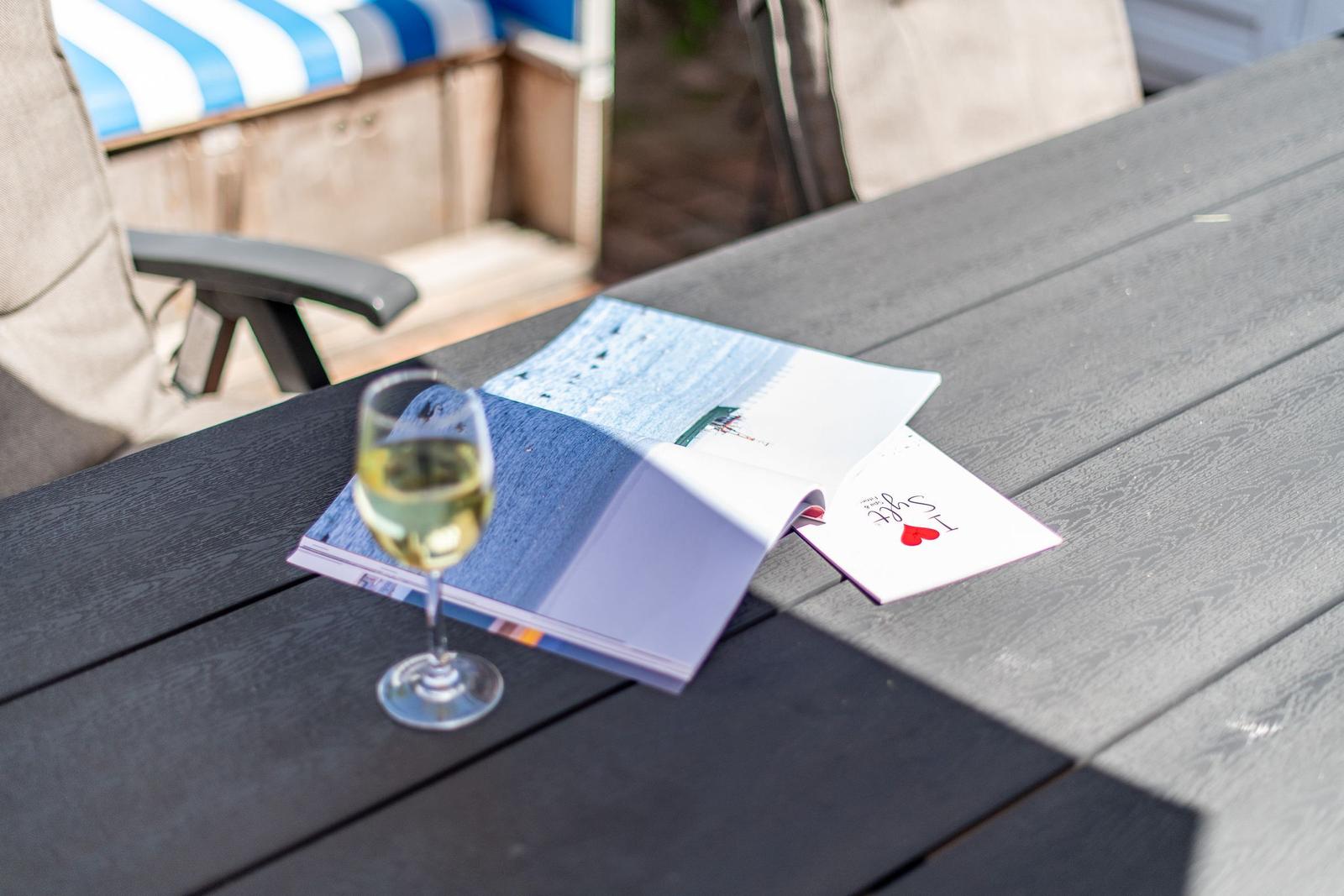 Ein Glas Weißwein steht auf einem Tisch neben einem Buch und einer Karte.