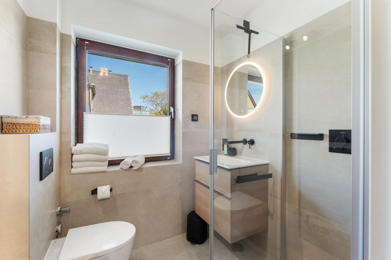 Badezimmer mit Dusche, Waschbecken und Fenster mit Blick.