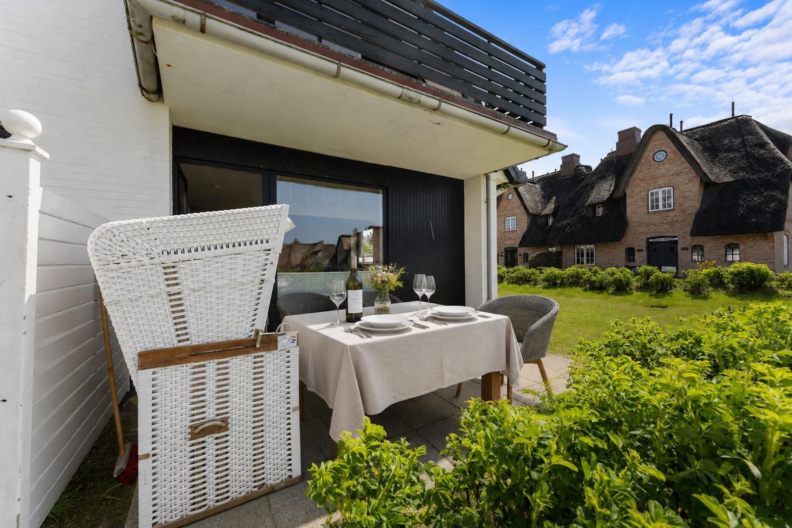 Terrasse mit gedecktem Tisch, weißen Stühlen und Blick auf traditionelle Dachhäuser.