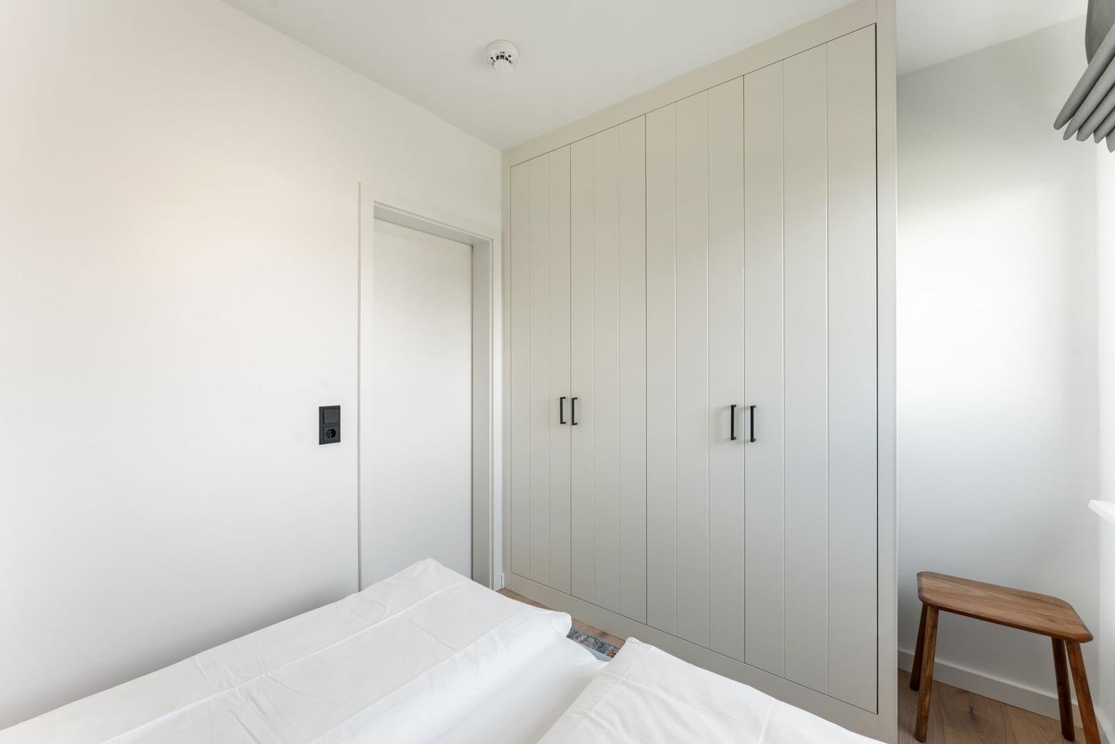 Schlafzimmer mit Bett, Kleiderschrank und Holzstuhl.
