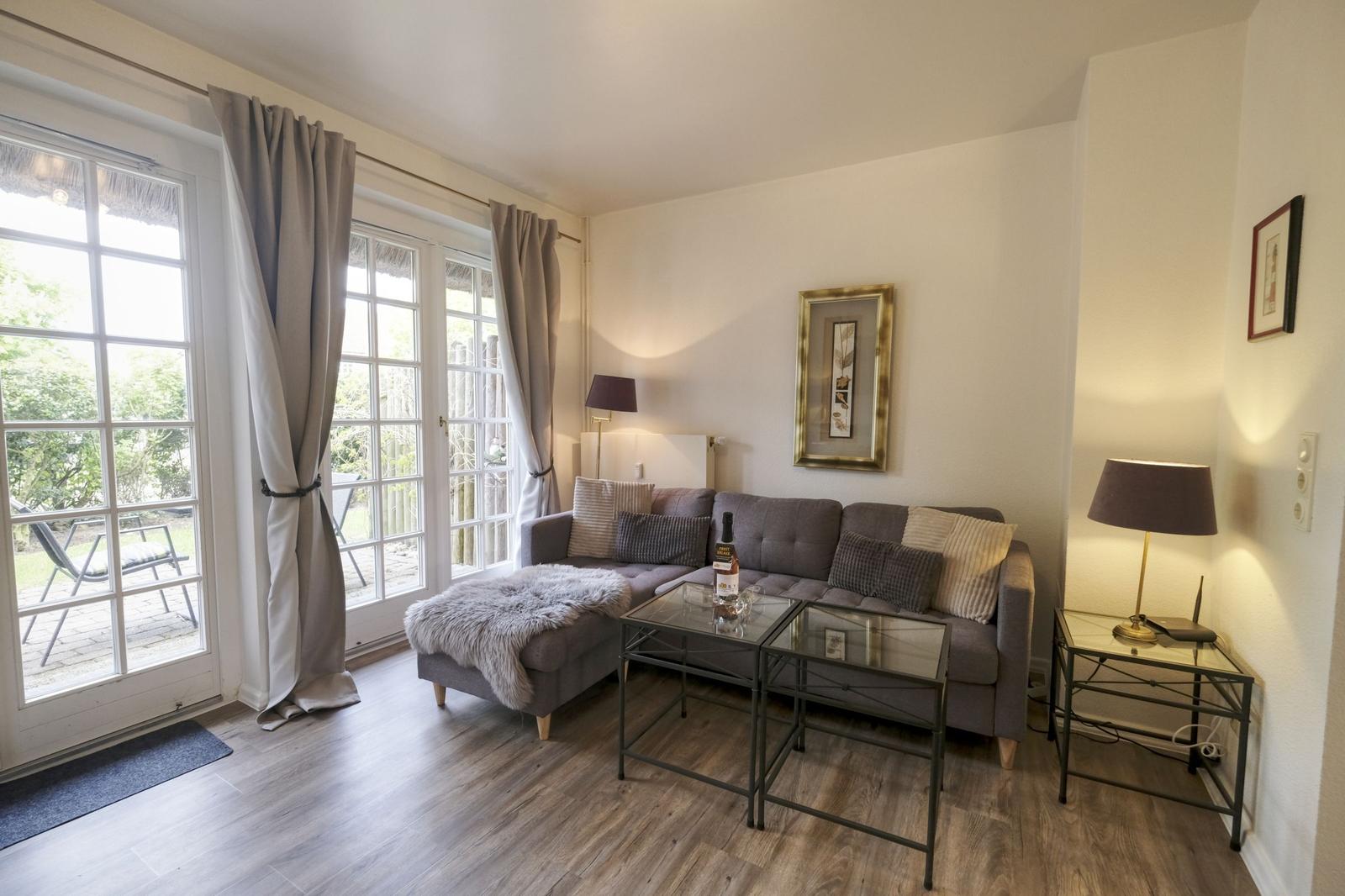 Wohnzimmer mit Sofa, Glas-Tisch und Blick auf den Garten.
