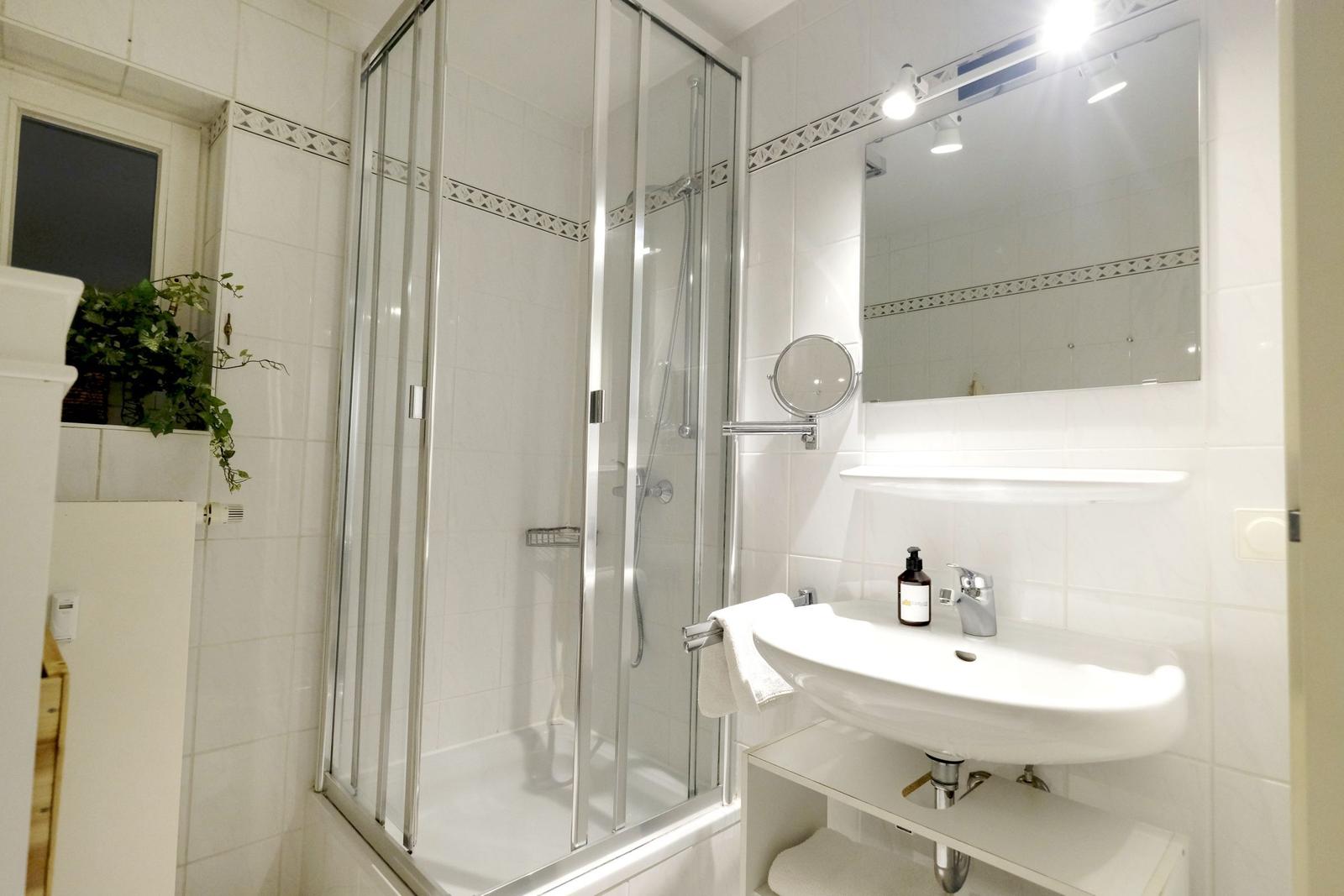 Badezimmer mit Dusche, Waschbecken und Spiegel.
