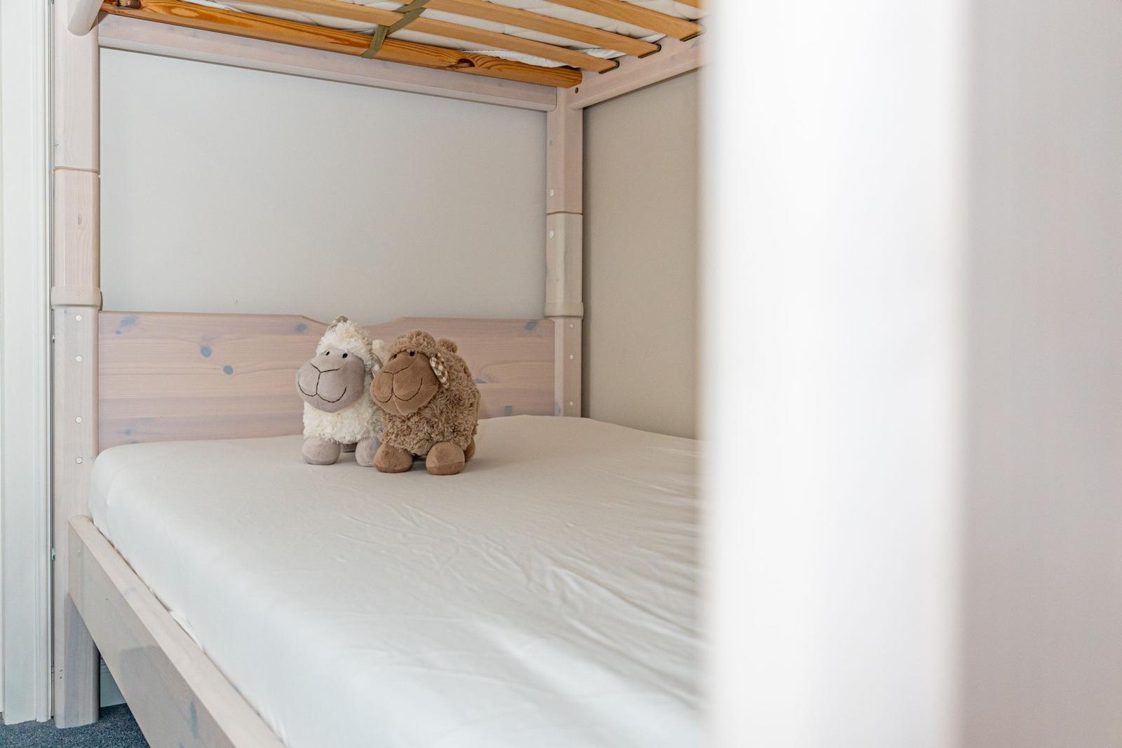 A bed with two stuffed sheep and a wooden frame.
