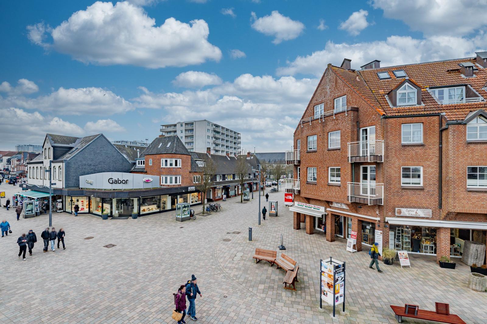 Market square with shops, benches, and a red brick building.