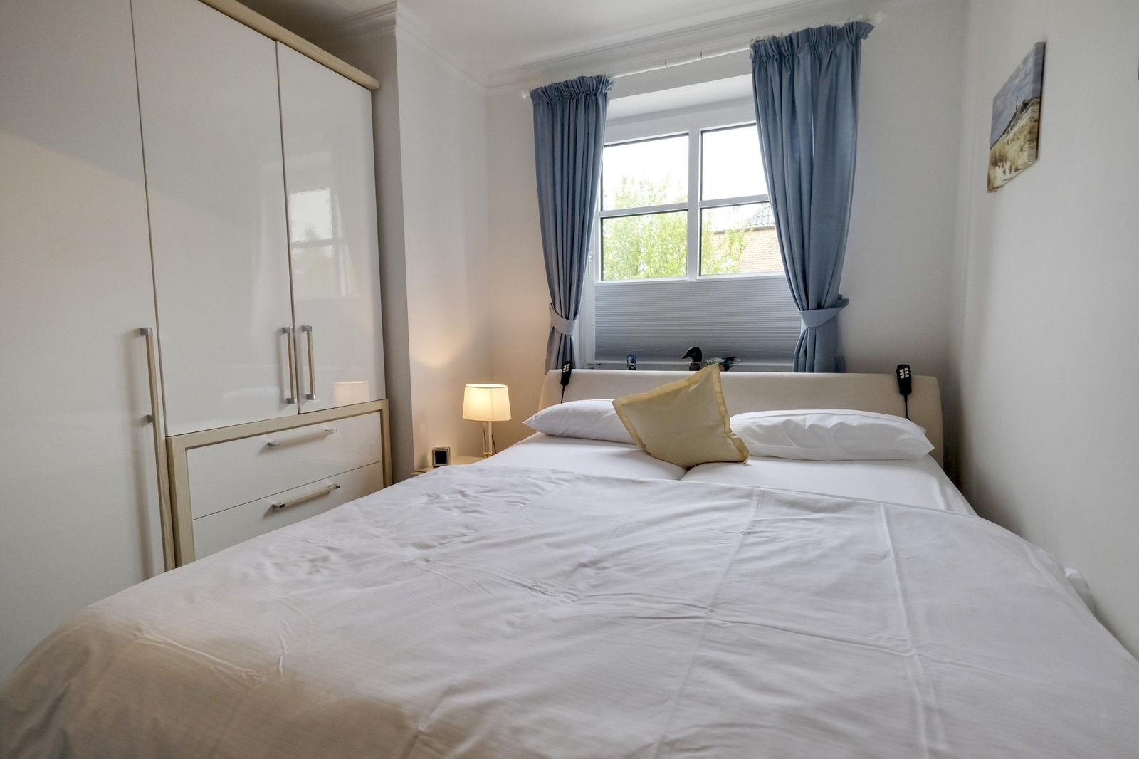 Bedroom with bed, wardrobe, and window with curtains.