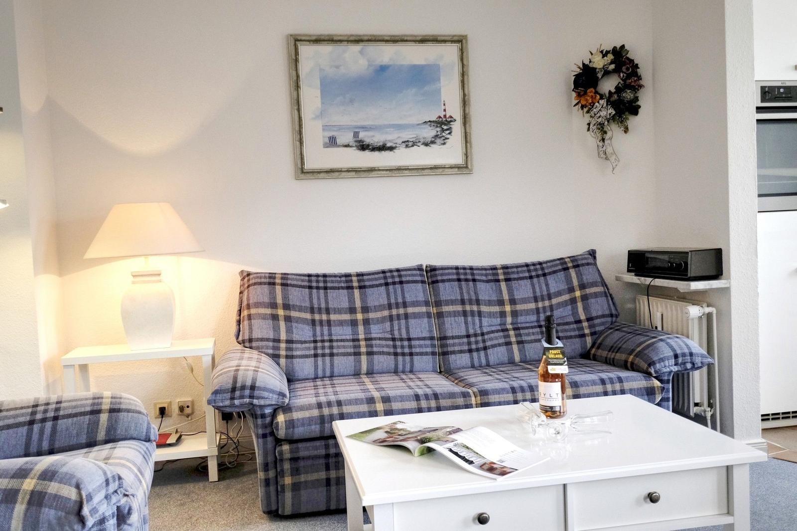 Living room with sofa and coffee table. Wall picture and lamp are visible.