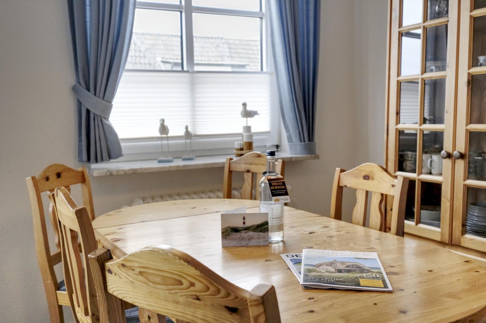 Wooden table with chairs, window with curtains, and glass cabinet in dining room.
