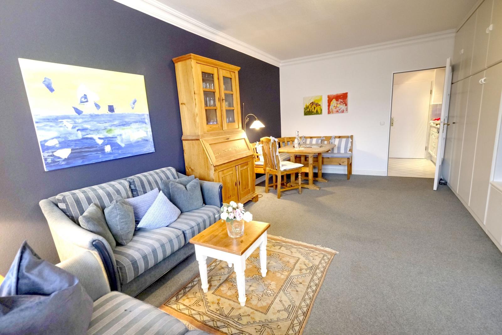 Wohn- und Essbereich mit Sofa, Tisch und Wandbild.