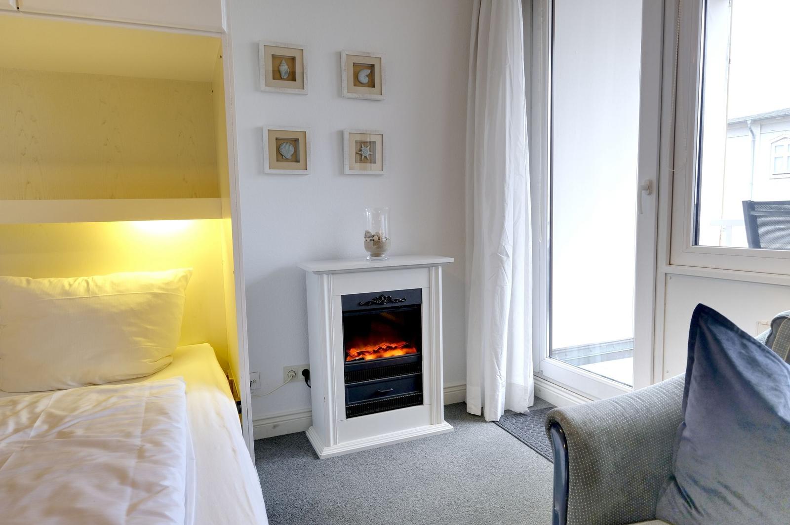 Schlafzimmer mit Bett, elektrischem Kamin und Fenster mit Blick.