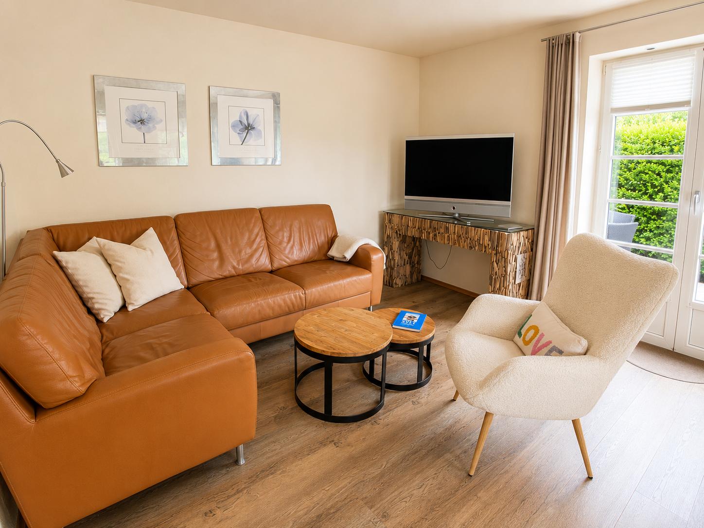 Ein Wohnzimmer mit braunem Sofa, einem Sessel und einem Fernseher.