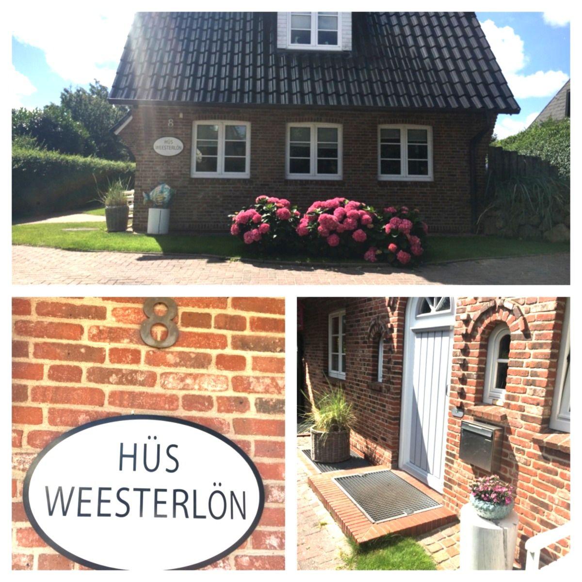 Haus mit rotem Backstein, weißen Fenstern und blühenden Hortensien vor der Tür.