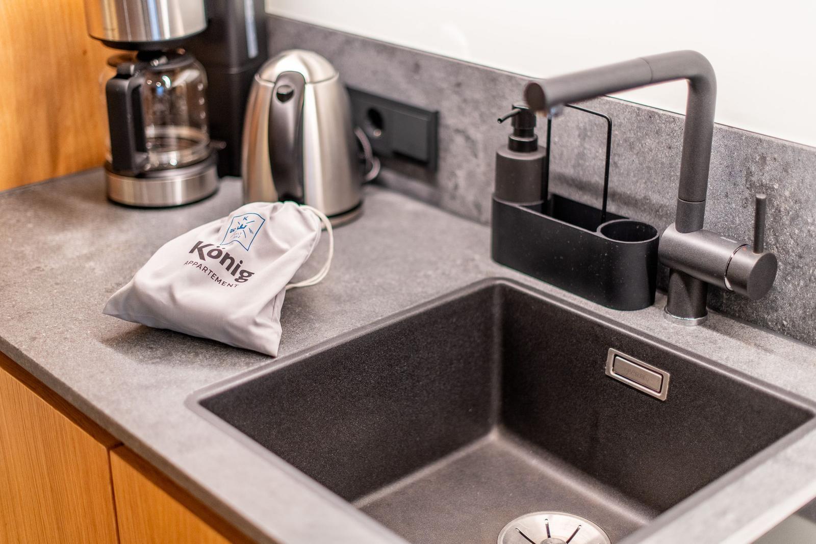 Kitchenette with sink, faucet, coffee maker, and kettle.