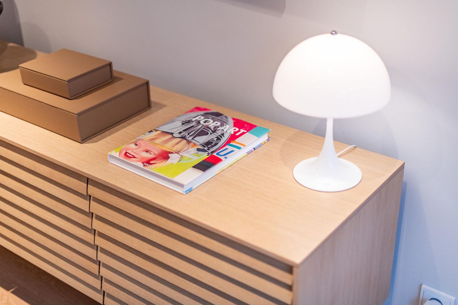 Wooden cabinet with lamp, book, and boxes on top surface.