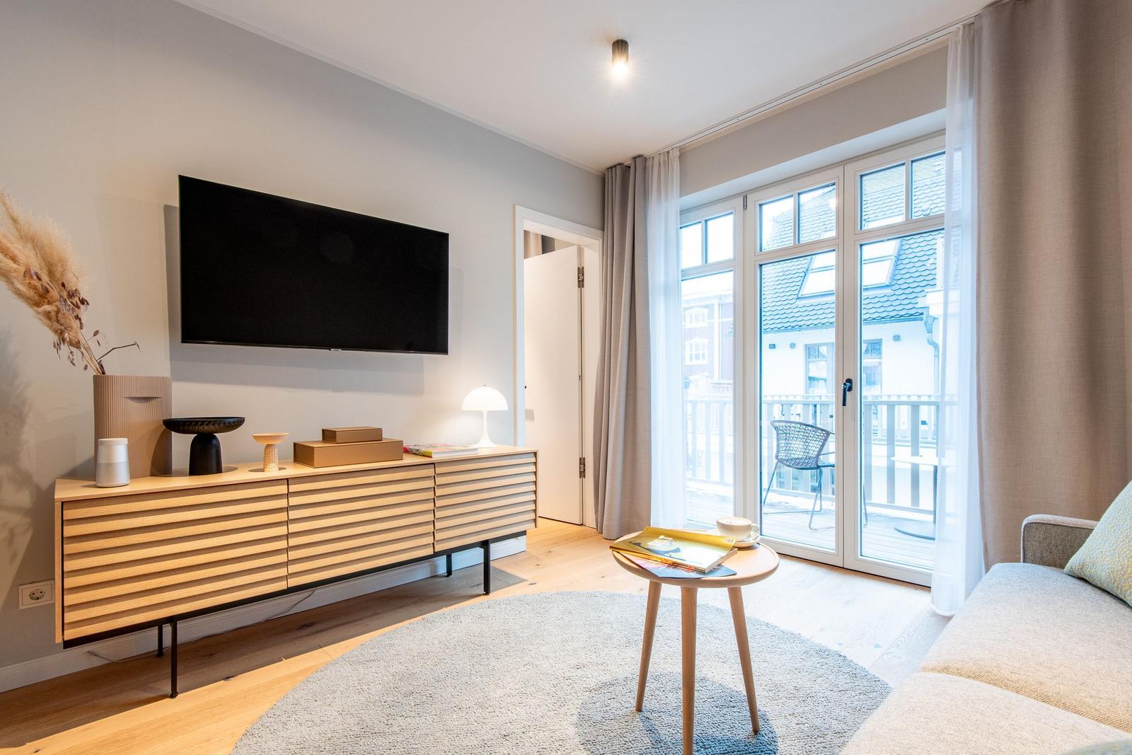 Living room with TV, sideboard, sofa, and balcony view.