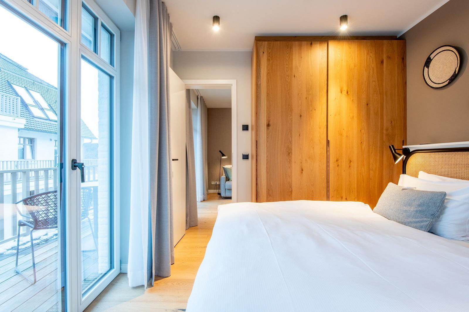 Bedroom with bed, wooden wardrobe, and balcony view.