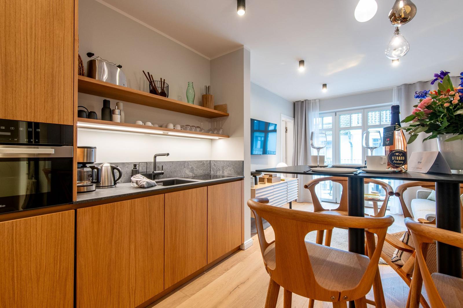 Kitchen with wooden cabinets and dining table with wooden chairs. View to balcony through window.