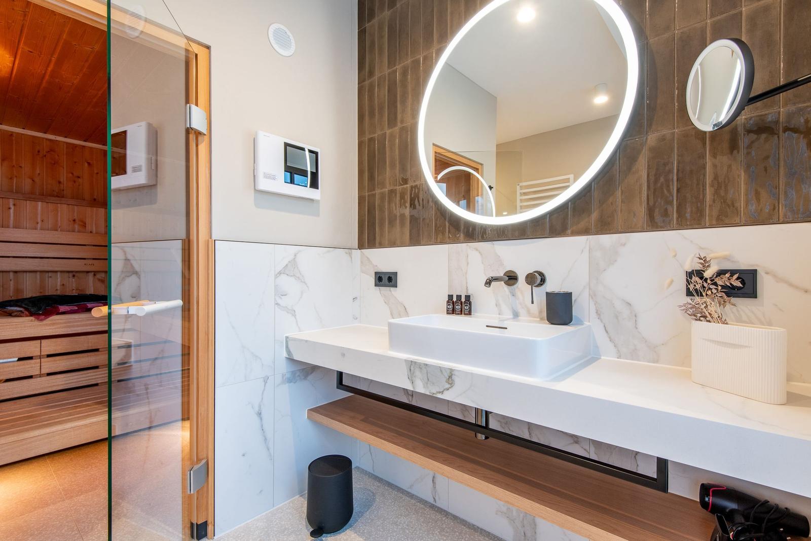 Bath with sauna, sink, and round mirrors