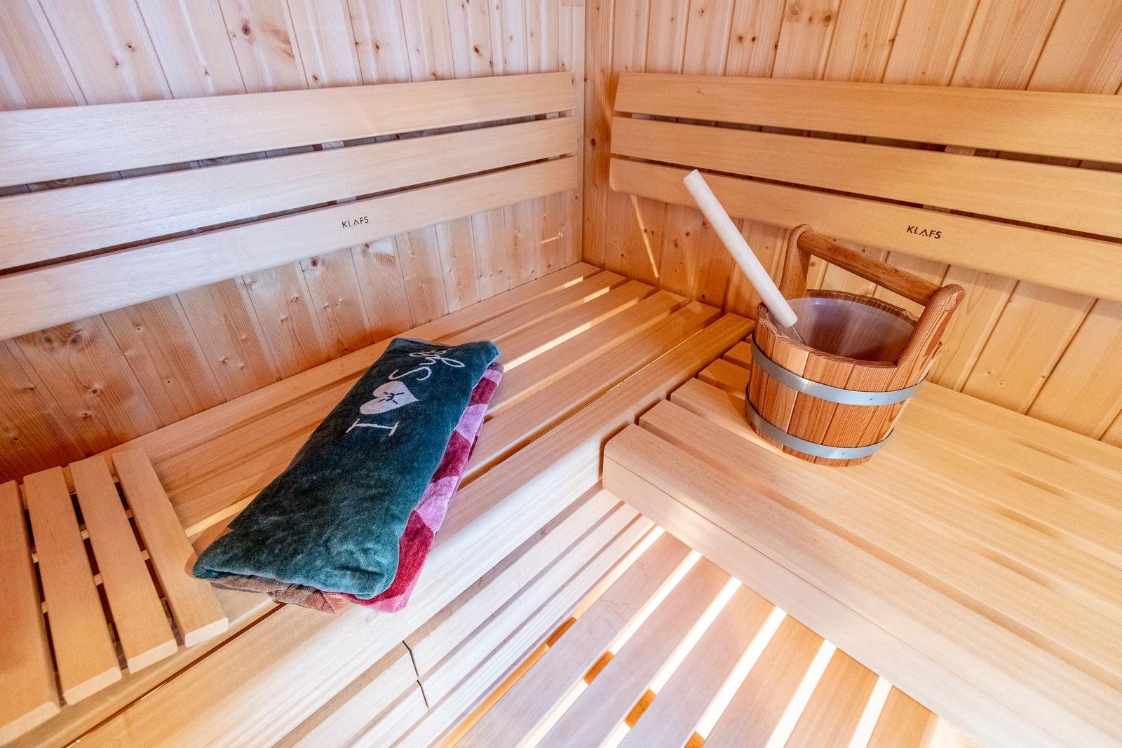 Sauna with wooden bench, bucket, and towel.