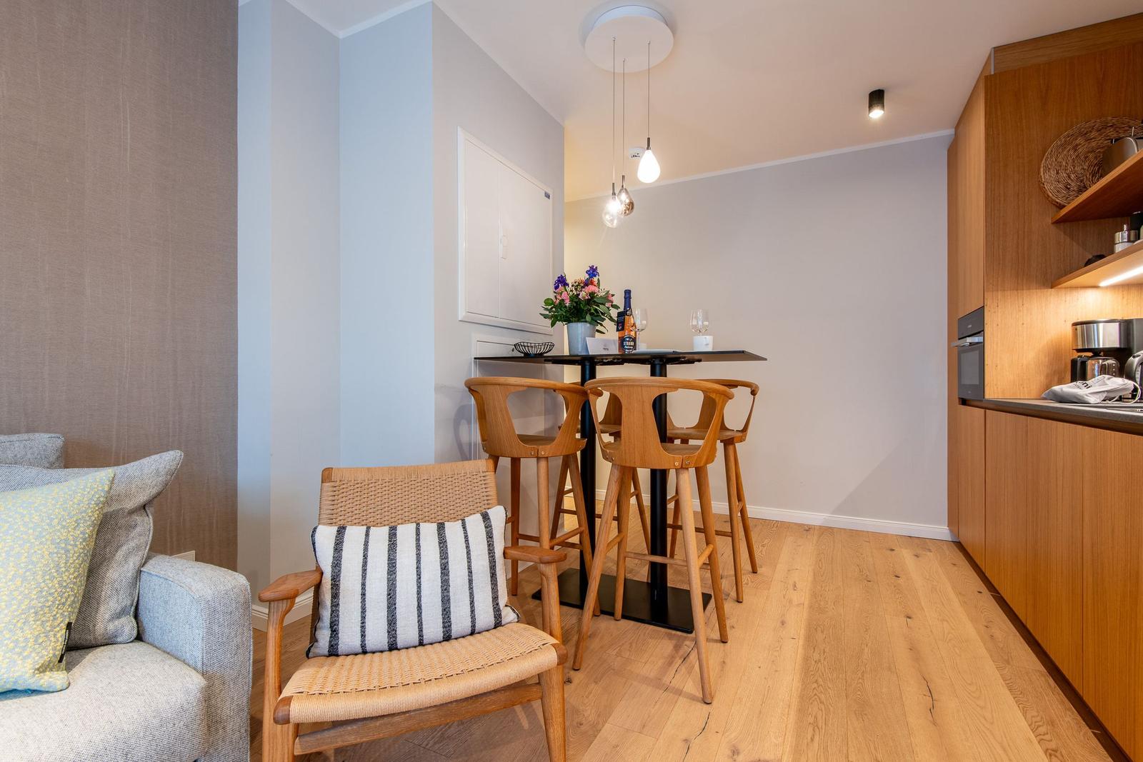 Kitchen with wooden furniture, dining table with chairs and sofa with cushions.