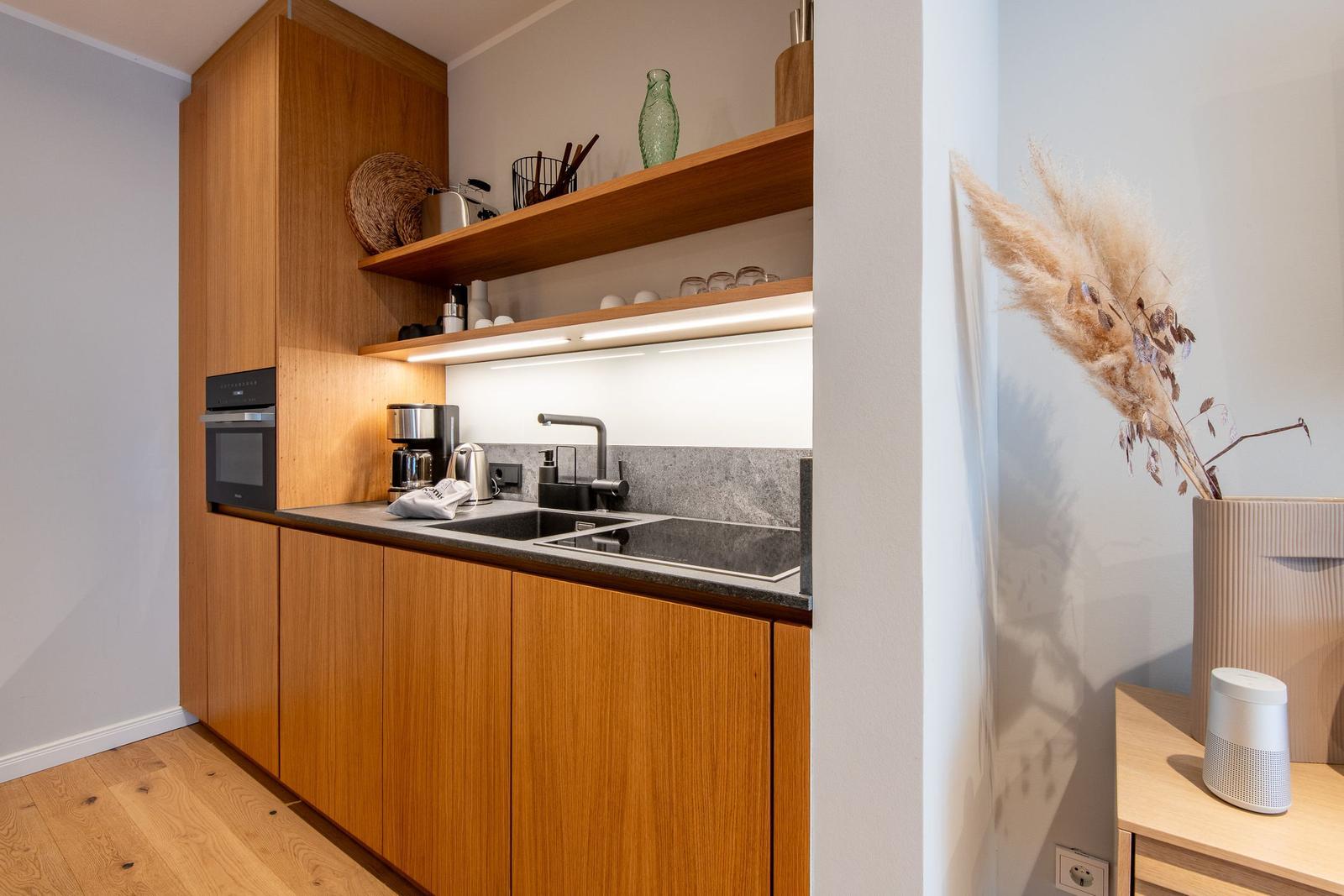 Kitchen with wooden cabinets, sink, and built-in oven. Decorative pampas grass in the background.