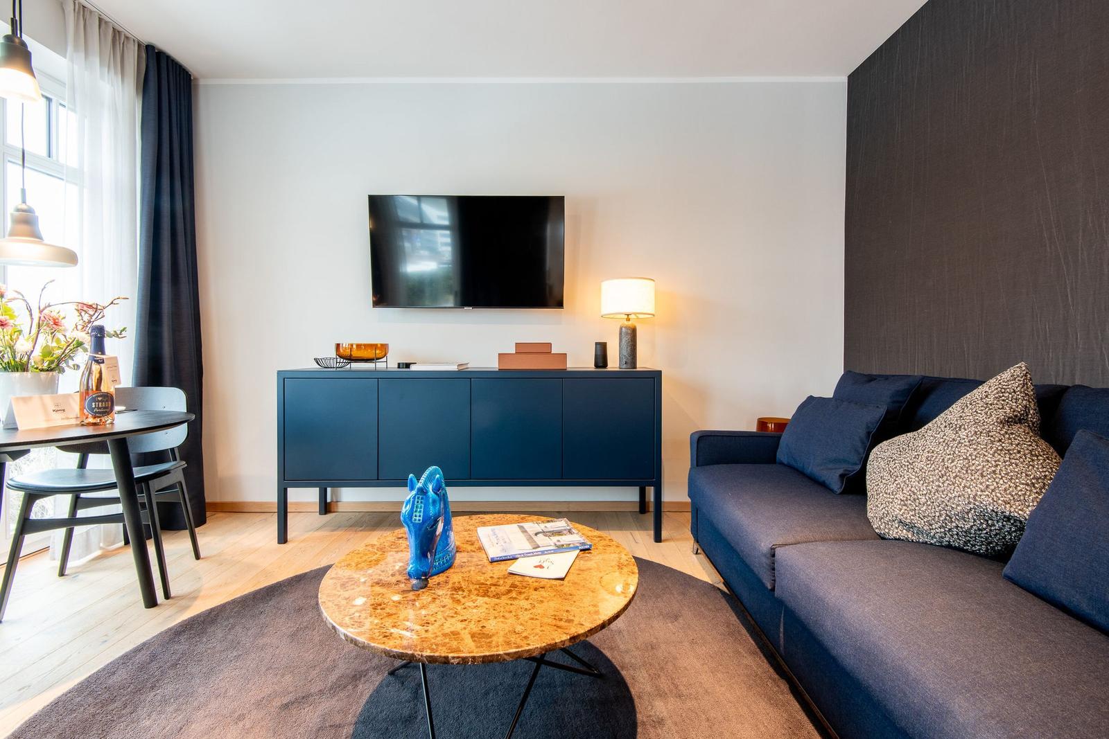 Wohnzimmer mit Sofa, Couchtisch und Fernseher an der Wand.