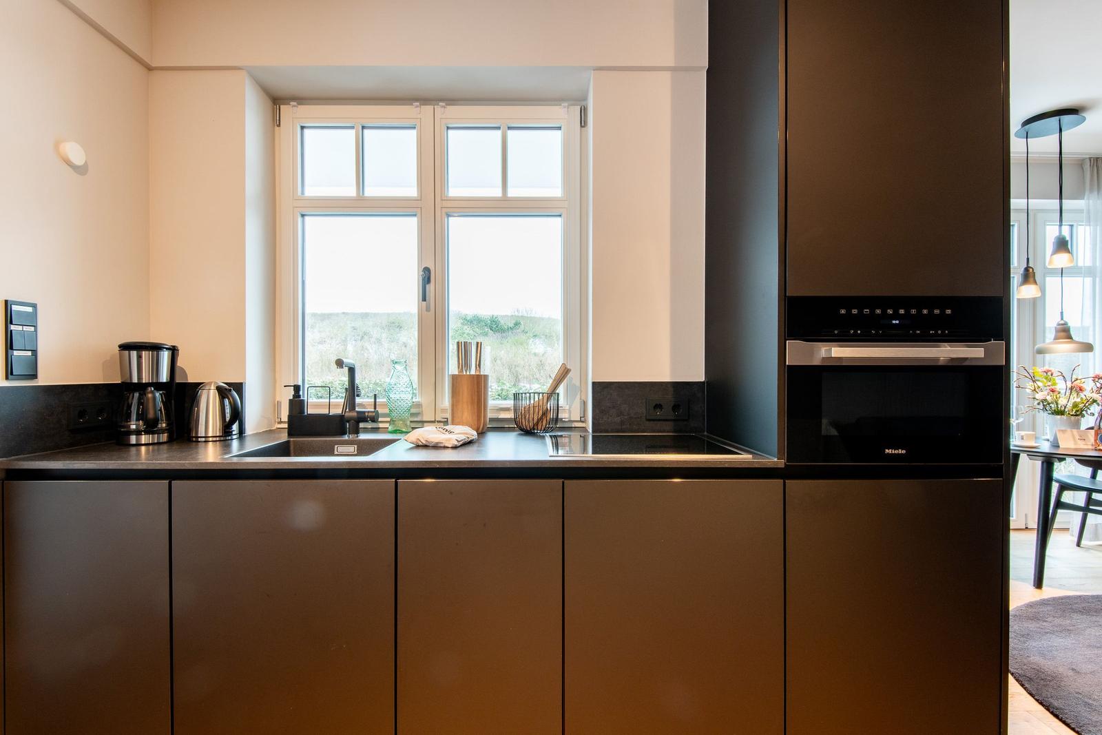 Moderne Küche mit Fenster, Spüle, Dunstabzug und integriertem Ofen.