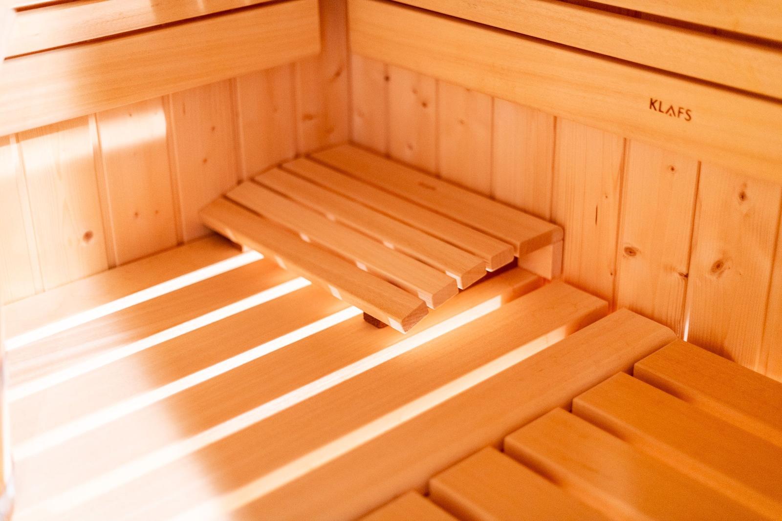 Sauna mit Holzbank und Wandverkleidung. Markenname KLAFS sichtbar.