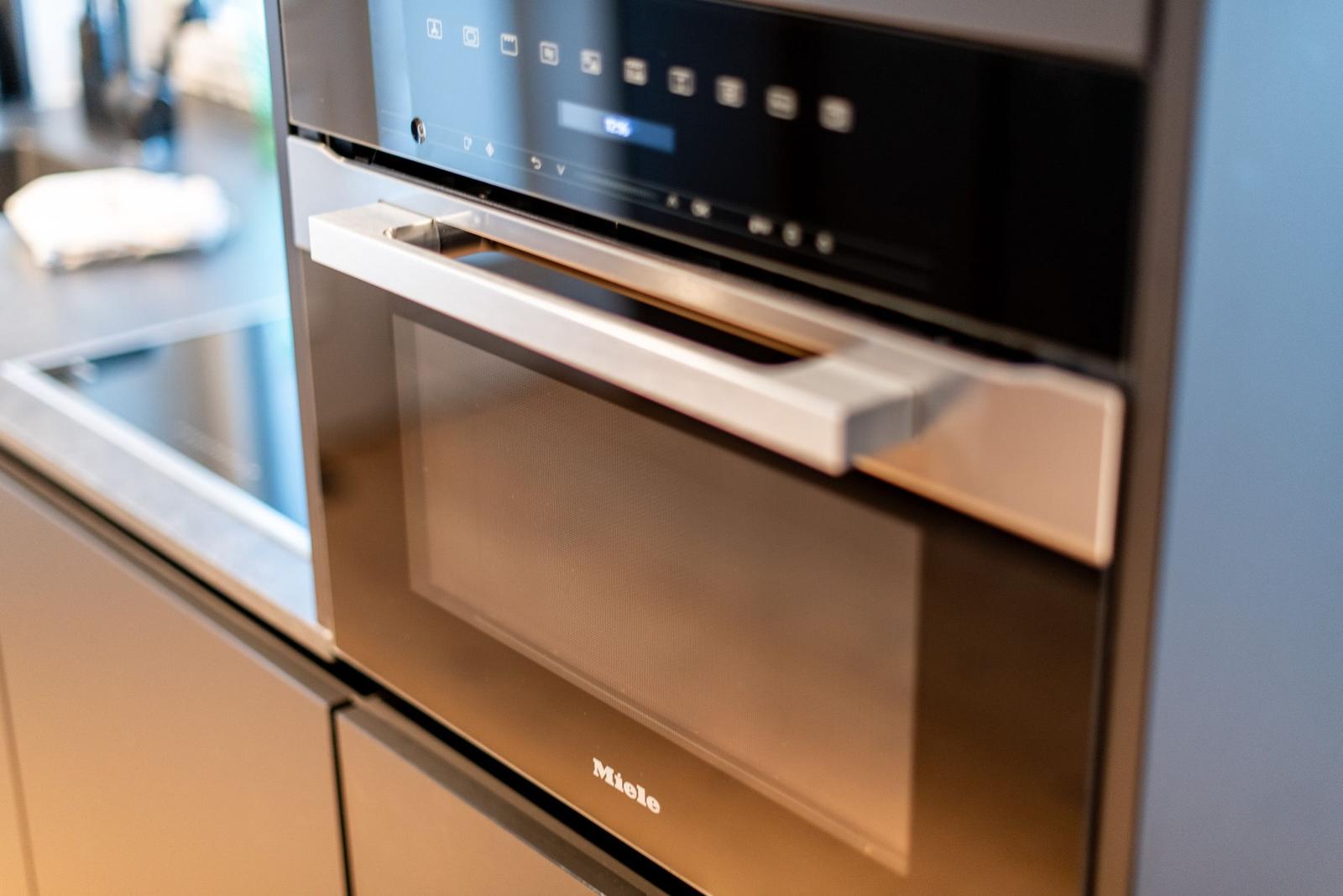 Ein eingebautes Miele-Küchenherd mit Touchdisplay und Edelstahlgriff.