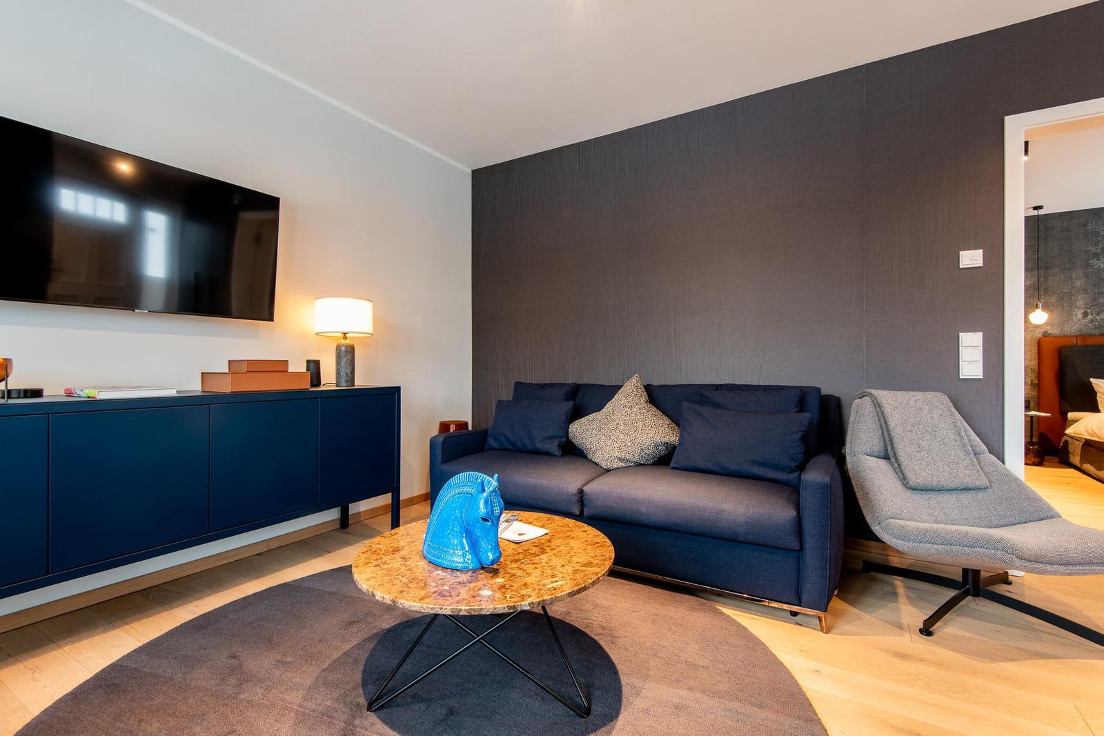 Wohnzimmer mit Sofa, Couchtisch und Fernseher an der Wand.
