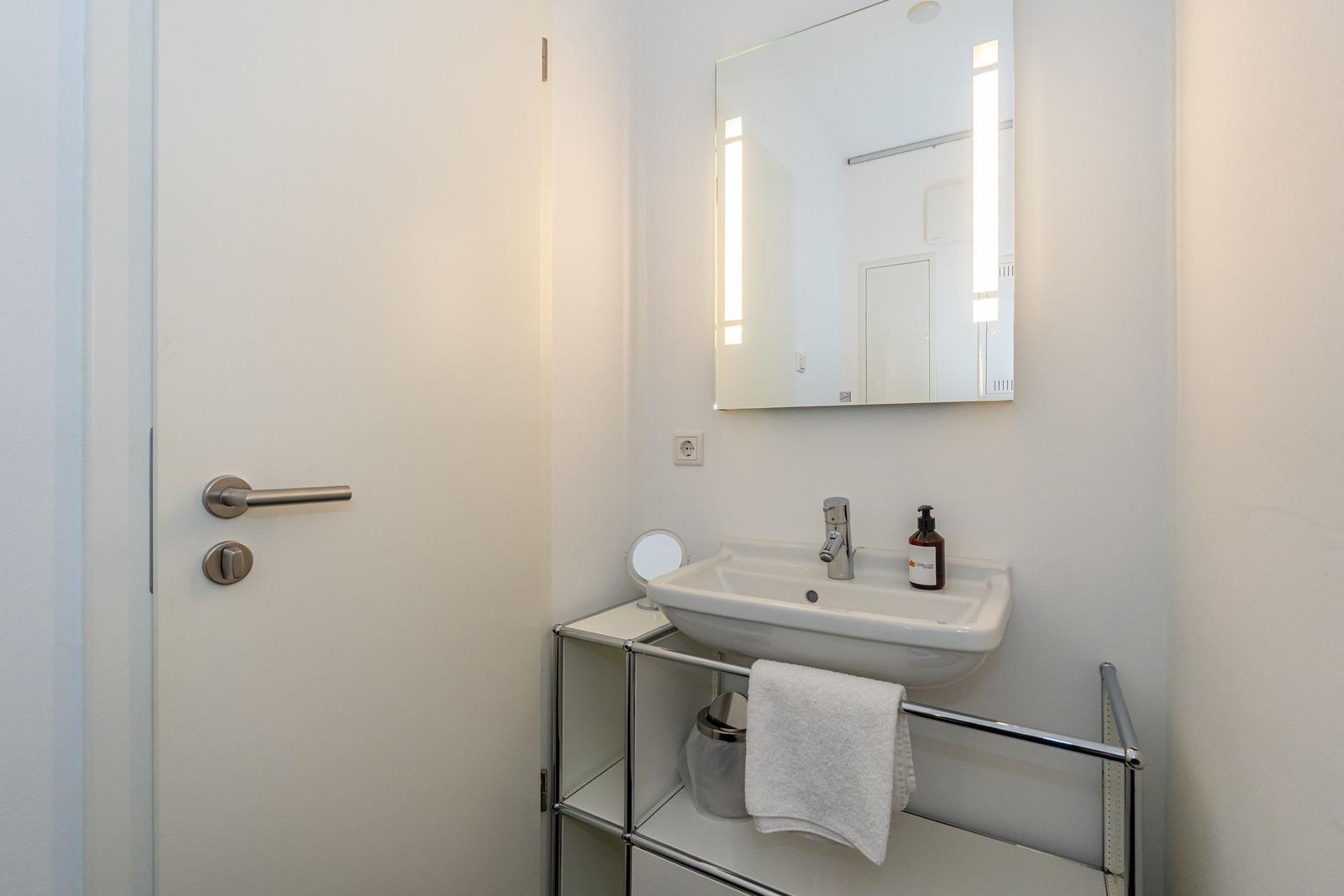 Badezimmer mit Waschbecken, Spiegel und Handtuchhalter.