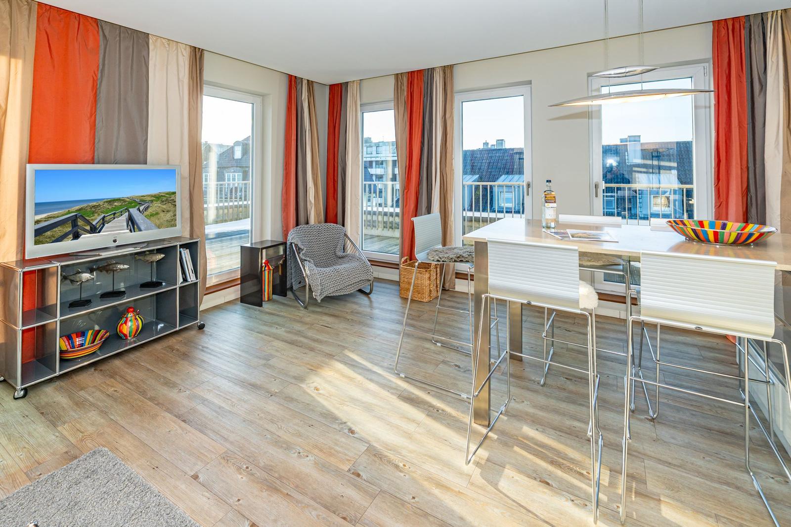 Wohn- und Essbereich mit TV, Sitzgelegenheit und Blick auf Balkon.