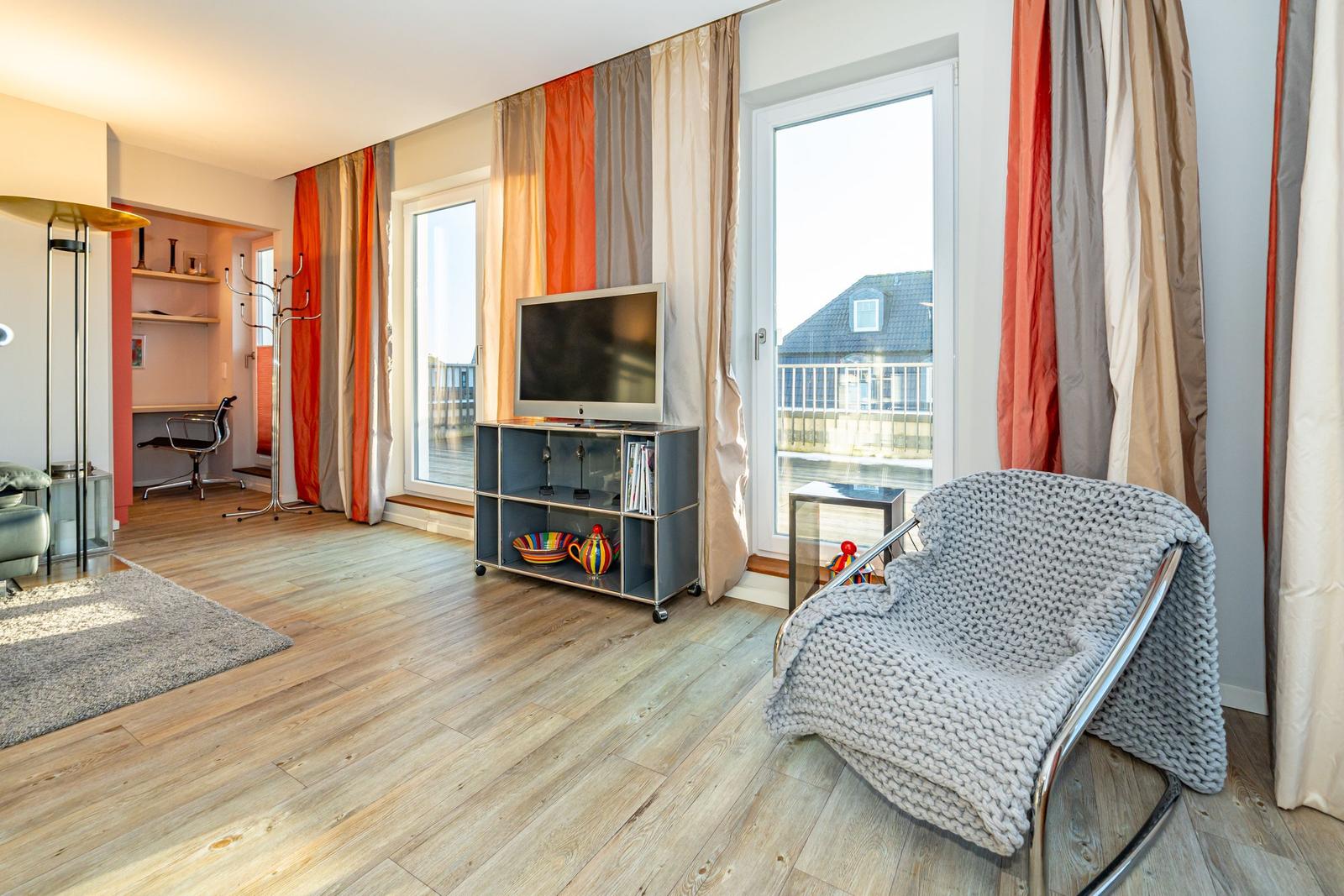 Wohnzimmer mit TV, Sessel und Fenster zur Aussicht