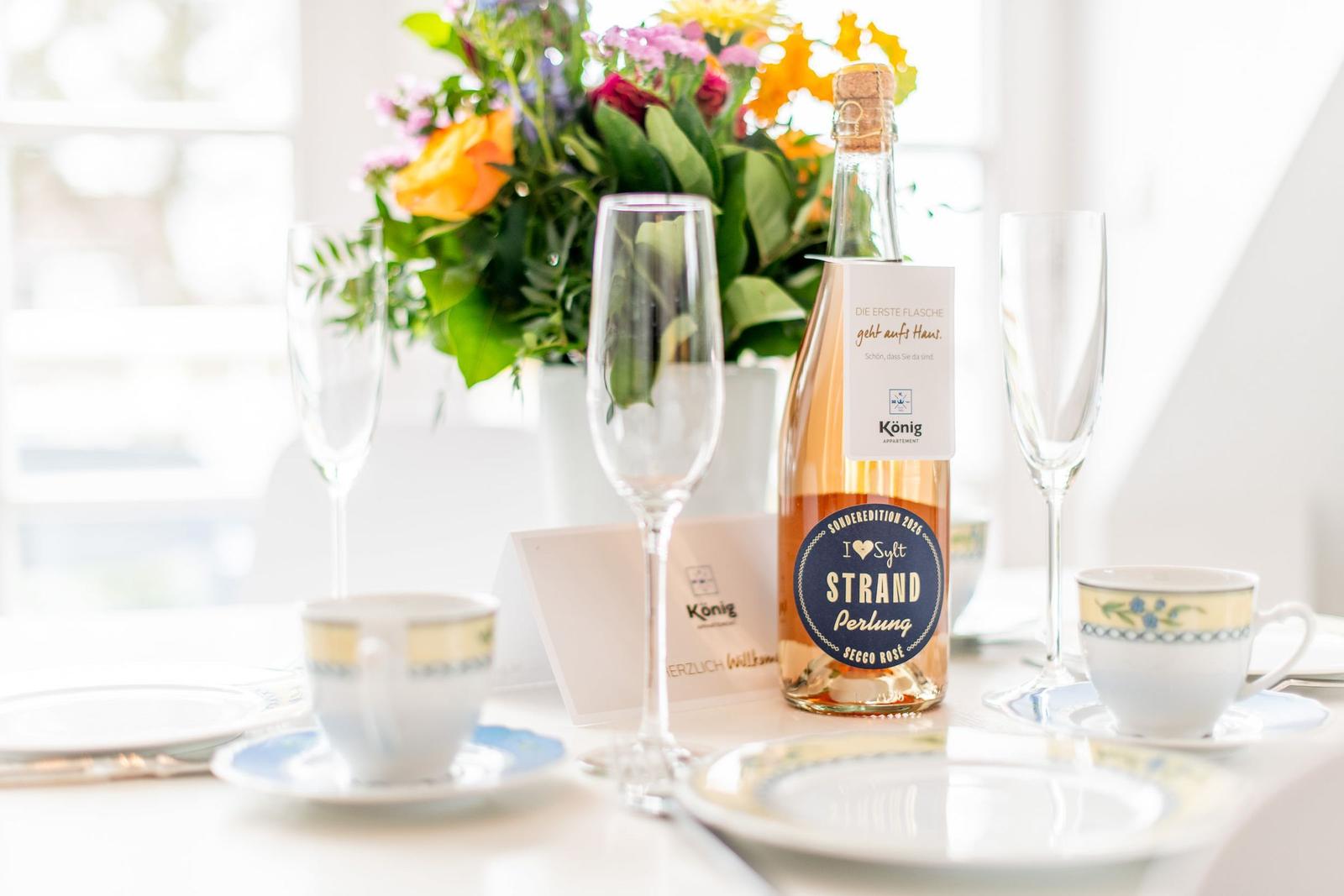 Tisch mit Blumen, Rosé und Gläsern für zwei Personen.