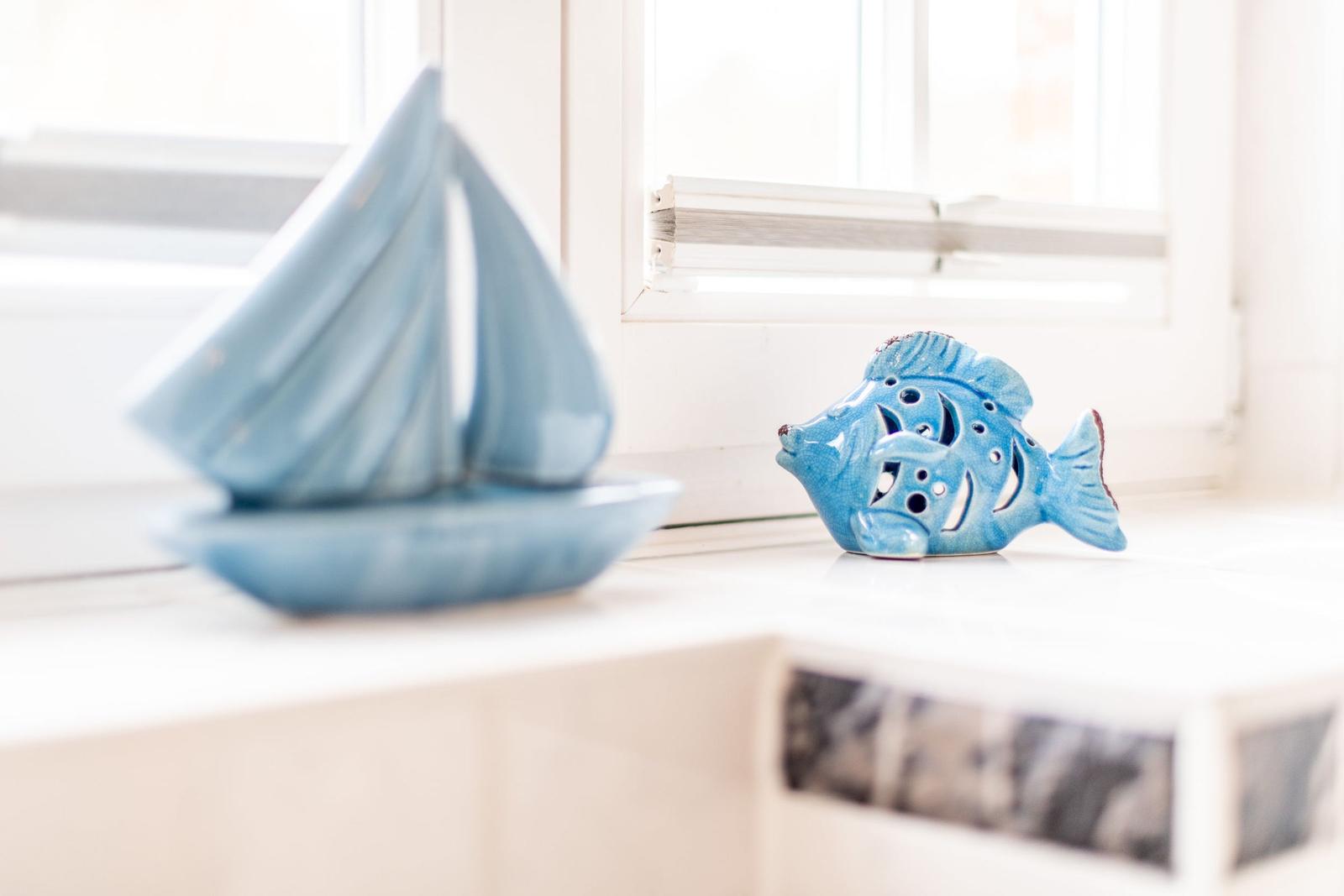Blauer Segelboot- und Fischfigur auf Fensterbank