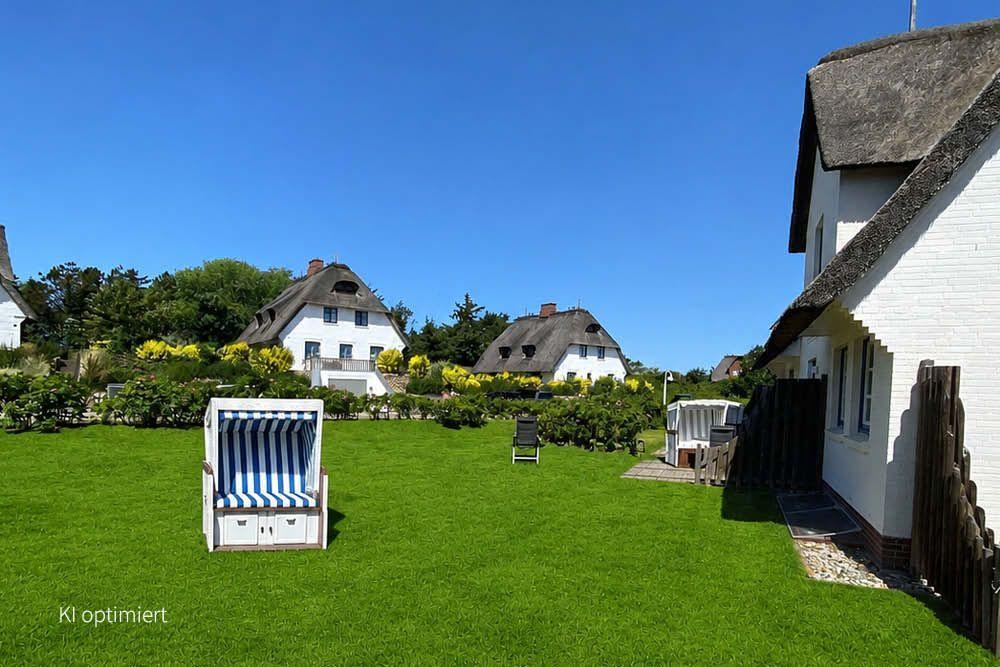 Grüner Garten mit Strandkorb, weißen Häusern und strohgedeckten Dächern unter blauem Himmel.