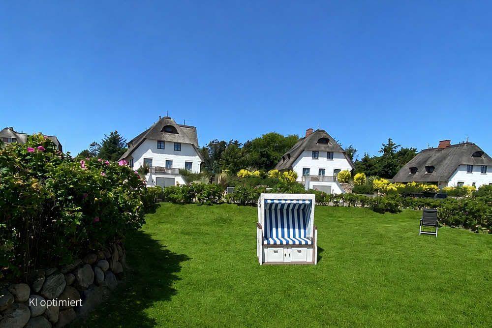 Grüner Garten mit Strandkorb und traditionellen Häusern im Hintergrund.