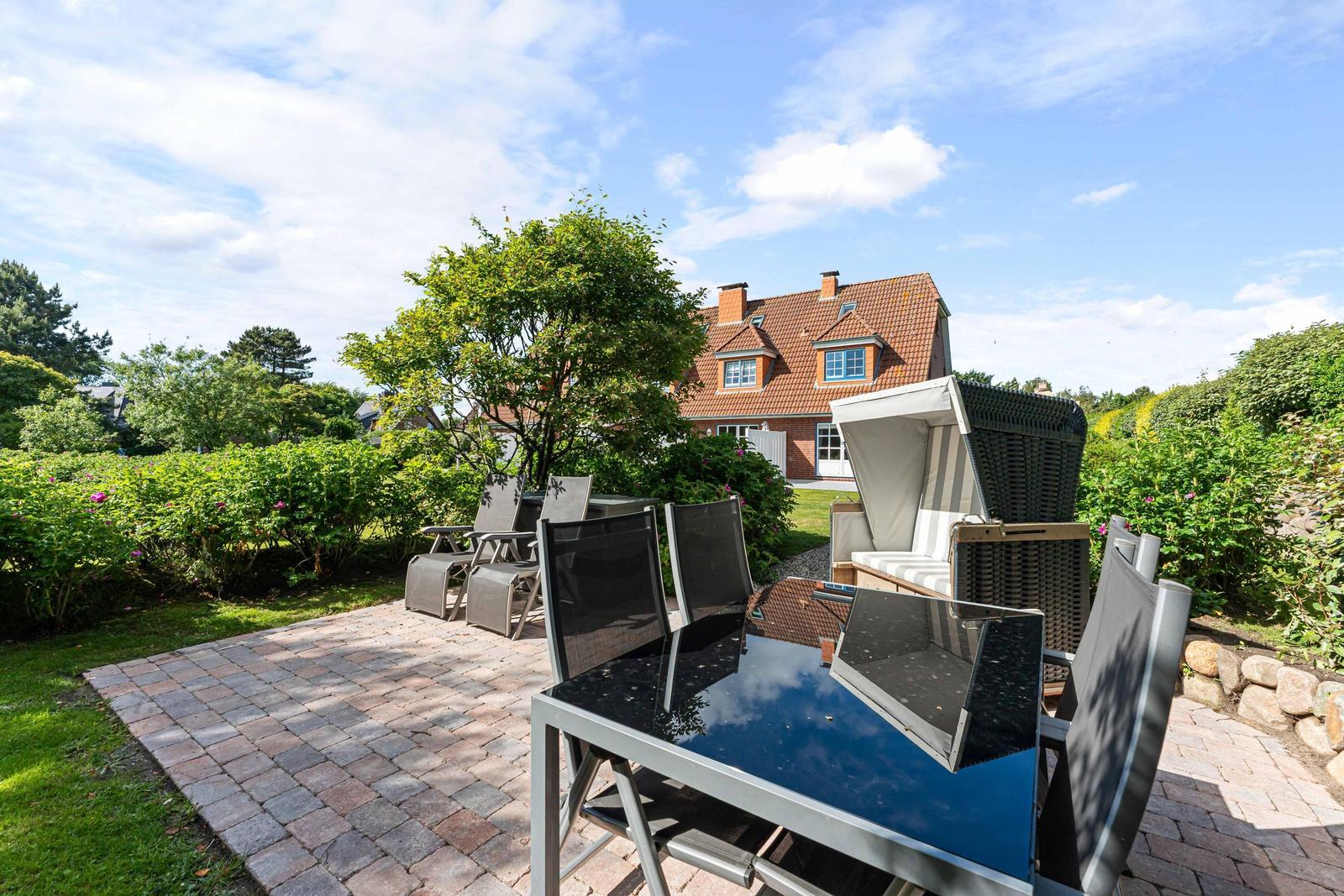 Terrasse mit Tisch und Stühlen, Blick auf ein Haus mit Garten.