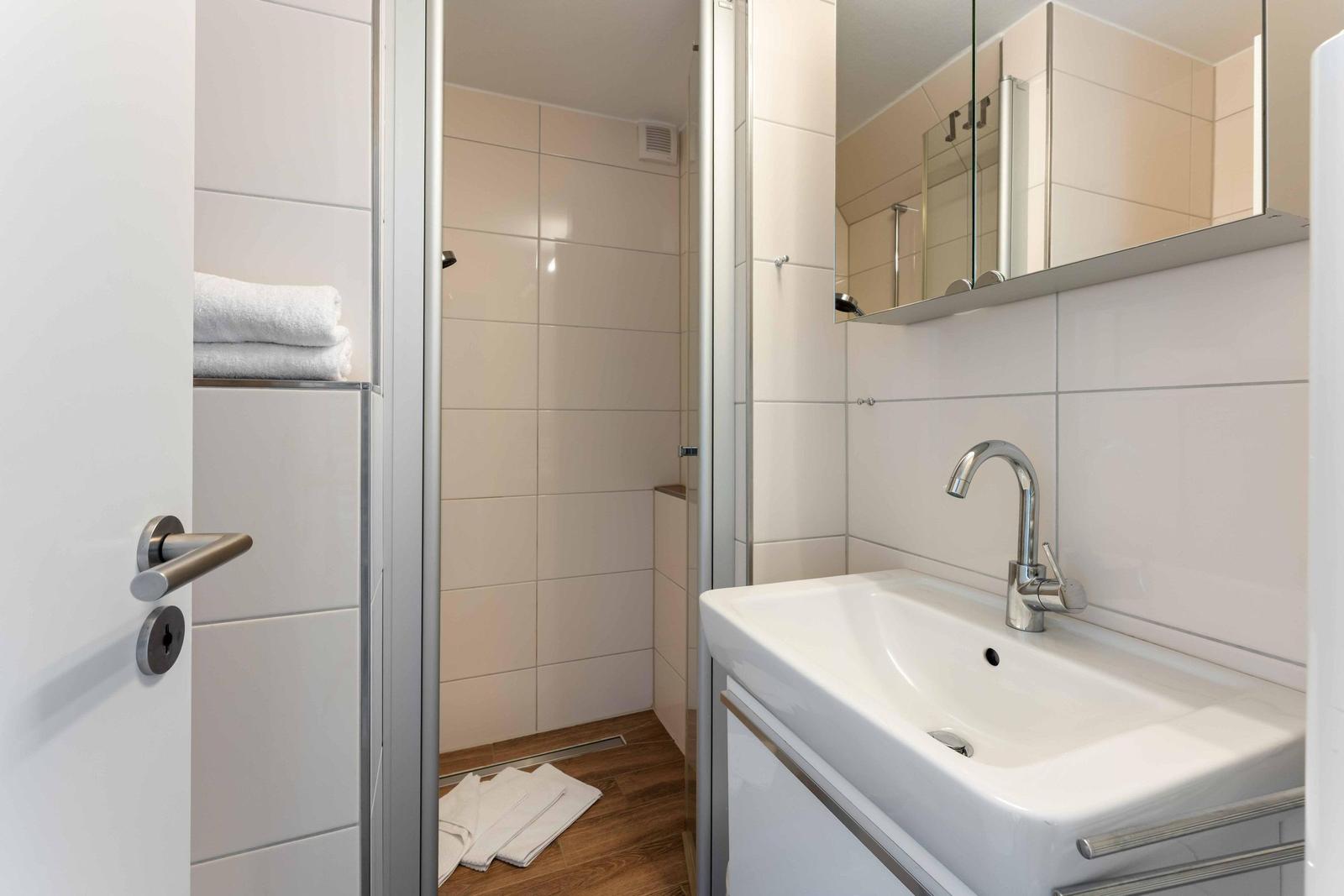 Badezimmer mit Dusche, Waschbecken und Spiegel