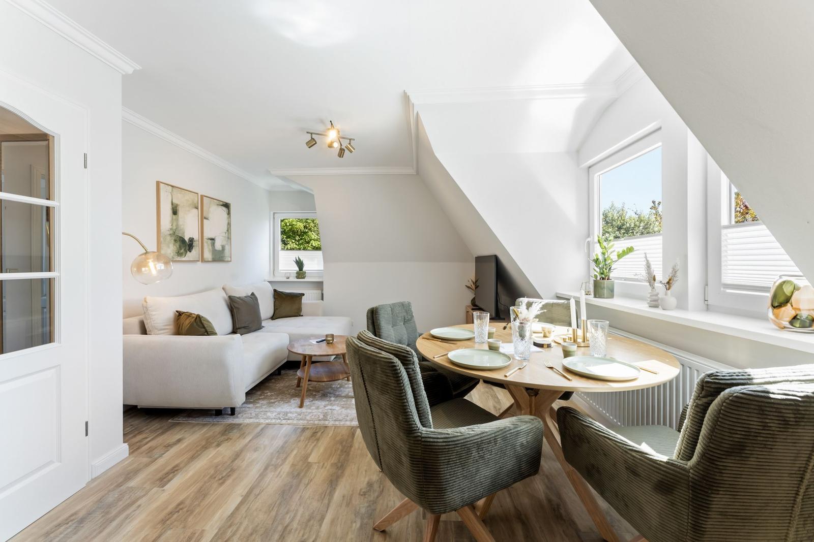 Living and dining area with sofa, table and chairs under sloped ceilings.
