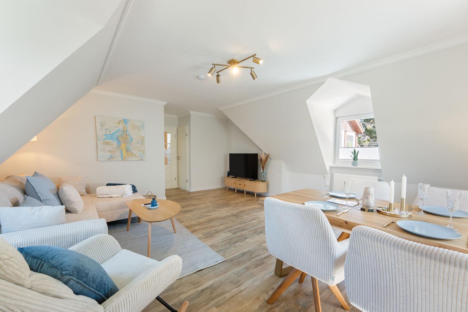 Wohn- und Essbereich mit Holzboden, Sofa, Esstisch und TV.