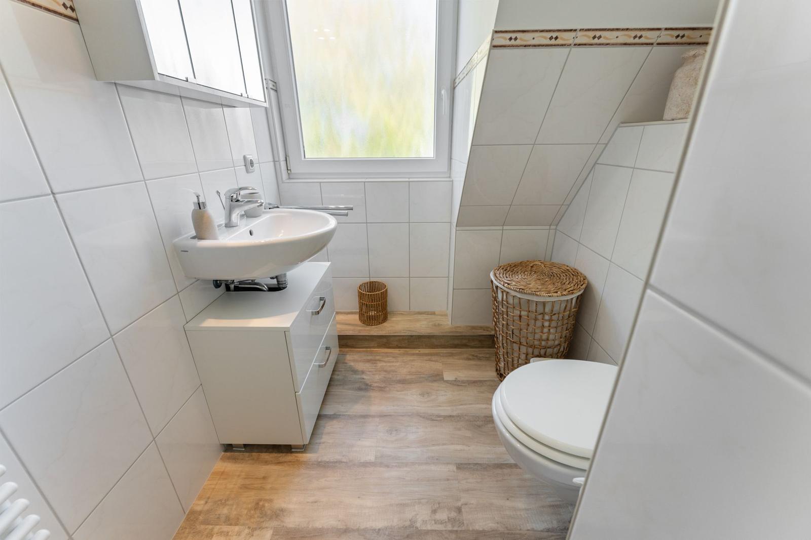 Badezimmer mit Waschbecken, Toilette und Fenster