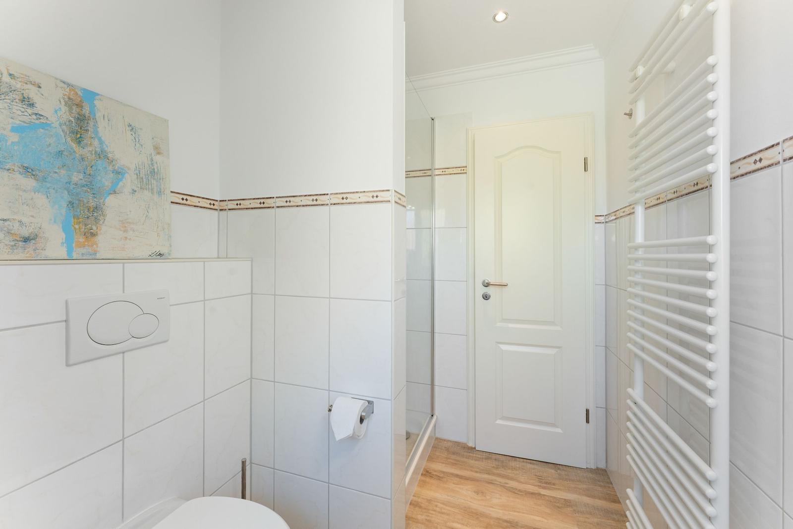 Badezimmer mit Toilette, Dusche und Heizkörper an der Wand.