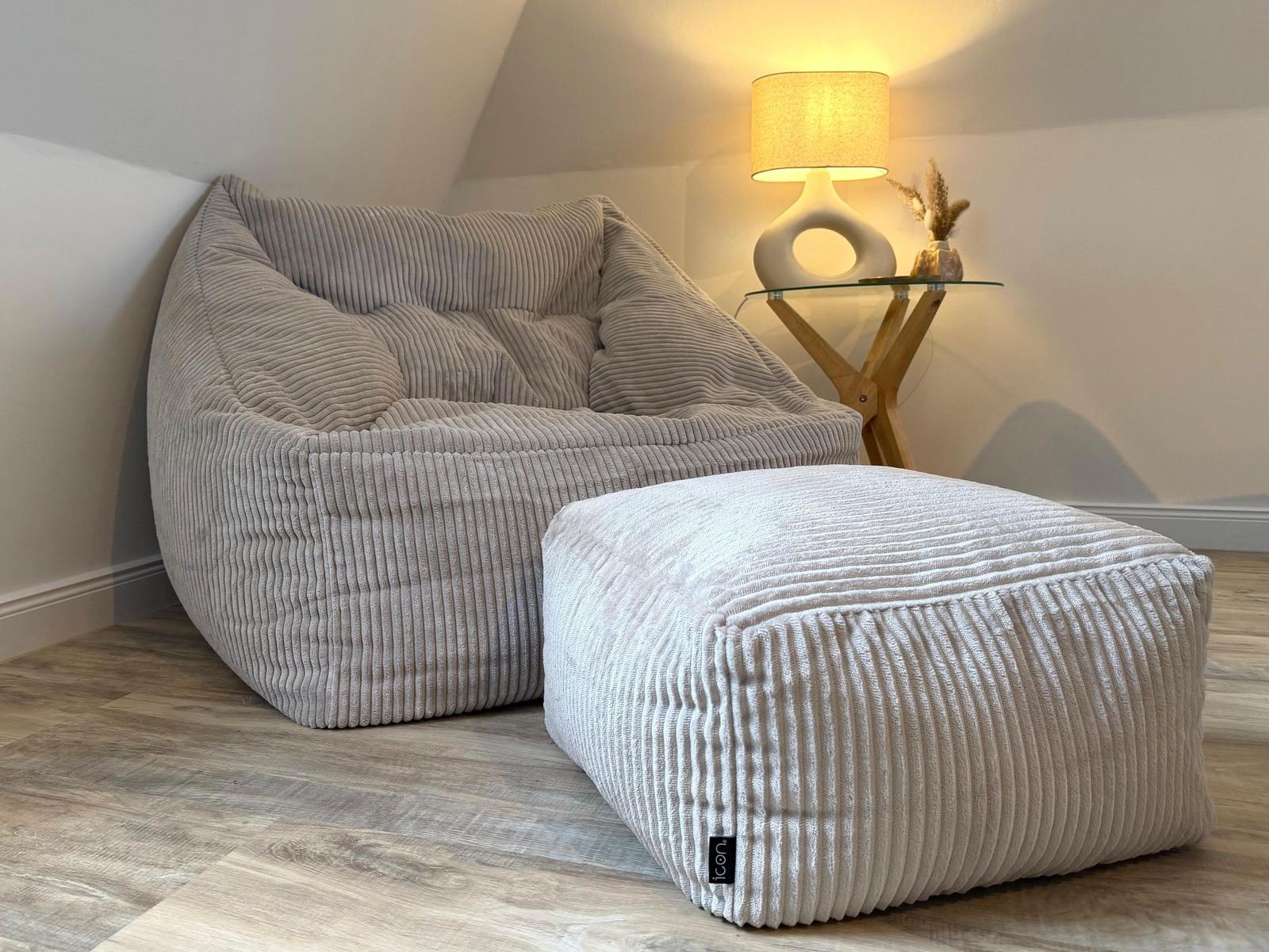Großer beiger Sessel und Hocker mit gerippter Textur stehen auf Holzboden.