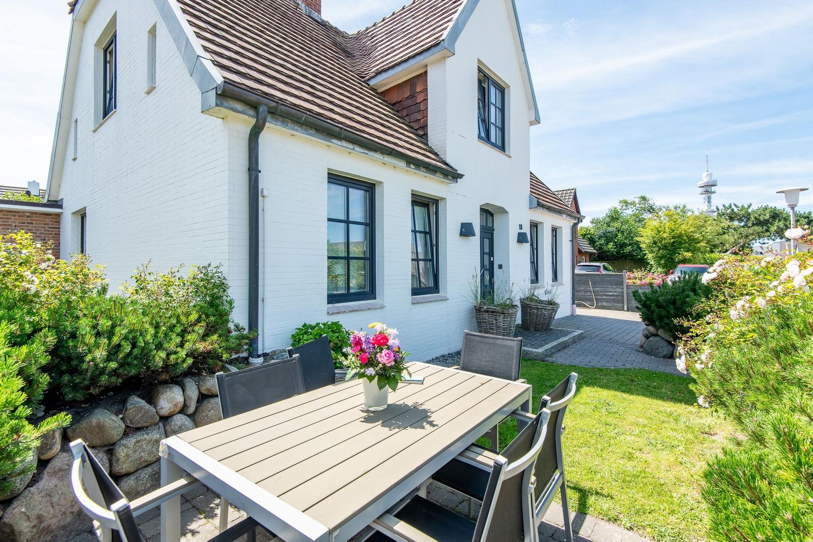 Haus mit Garten, Terrasse und Tisch mit Stühlen. Blick auf Fernmeldeturm.