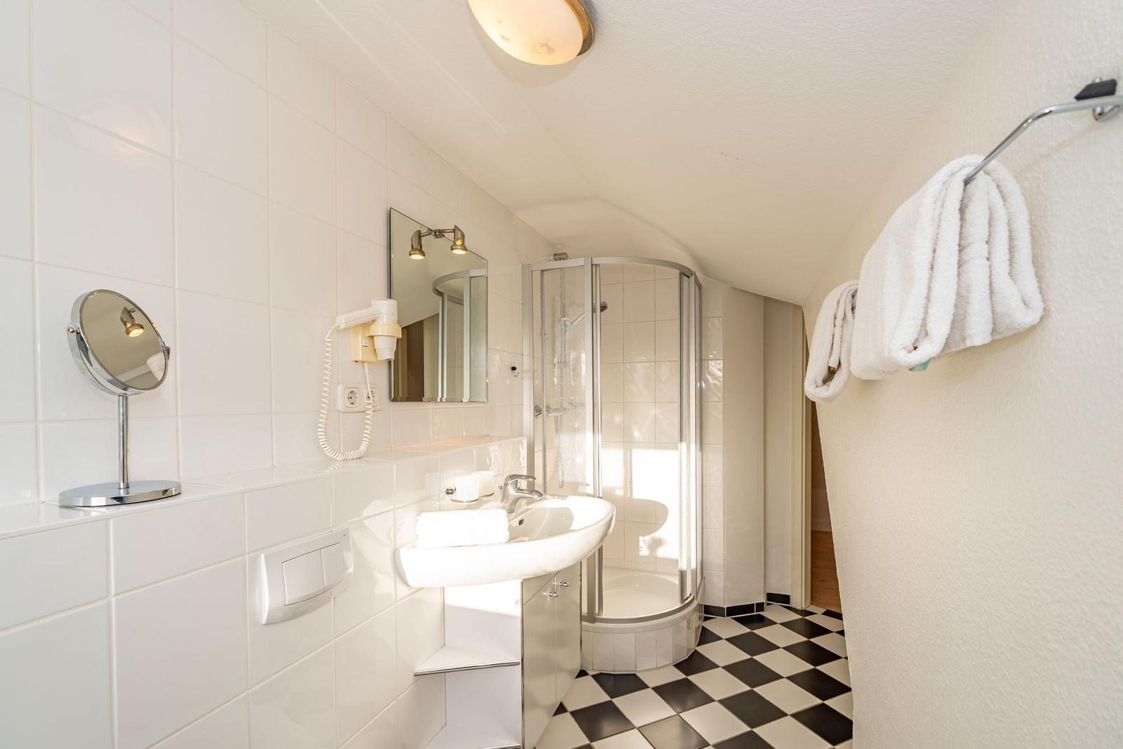 Badezimmer mit Dusche, Waschbecken und Handtuchhalter.