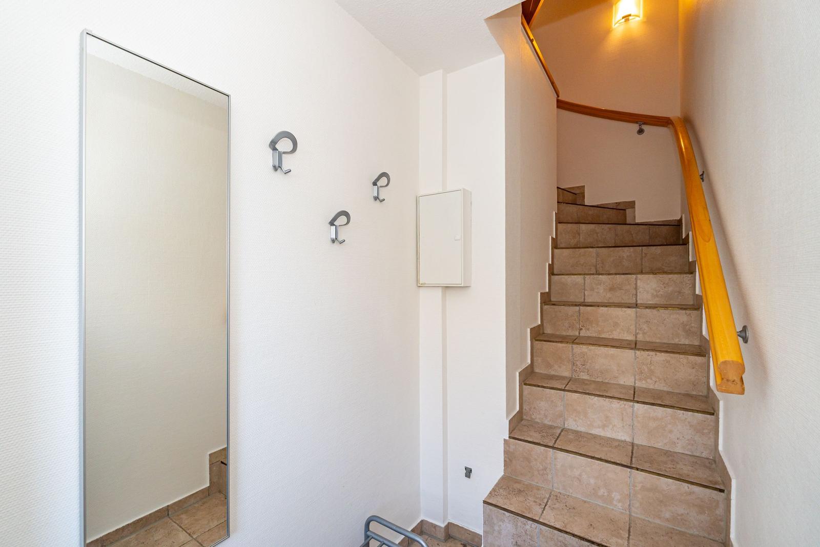 Halle mit Spiegel, Haken und Treppe mit Holzgeländer.