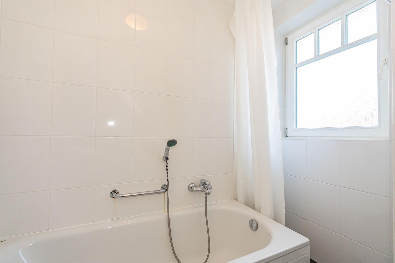 Bad mit Badewanne, Duschkopf und Fenster